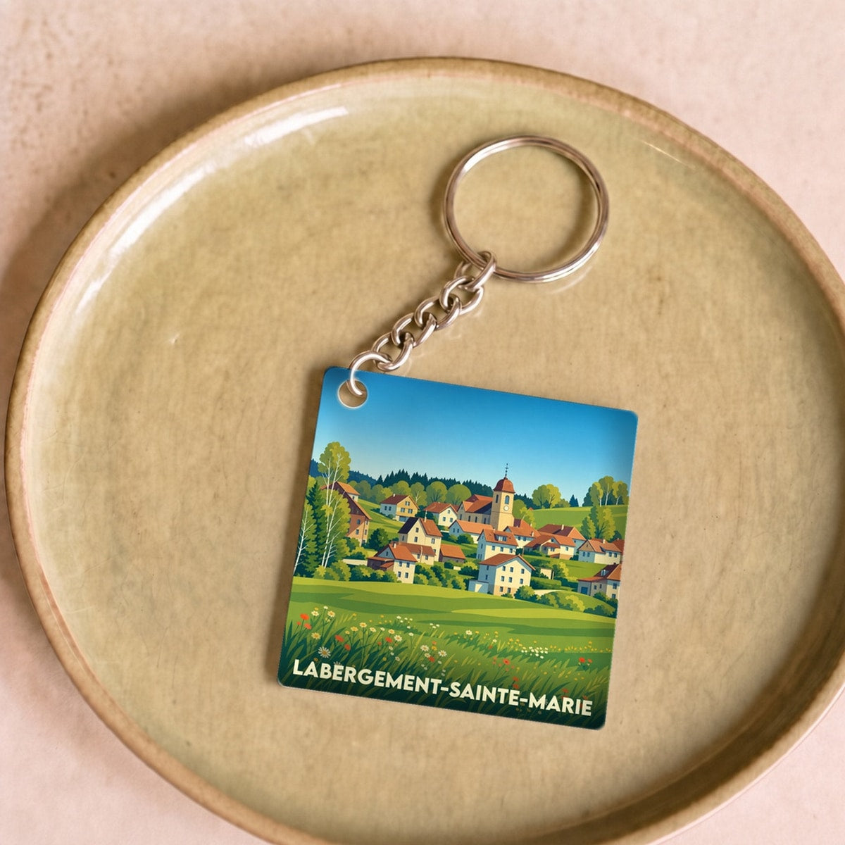 Porte-clés souvenir de la ville de Labergement-Sainte-Marie avec une illustration stylisée d'un village de montagne.