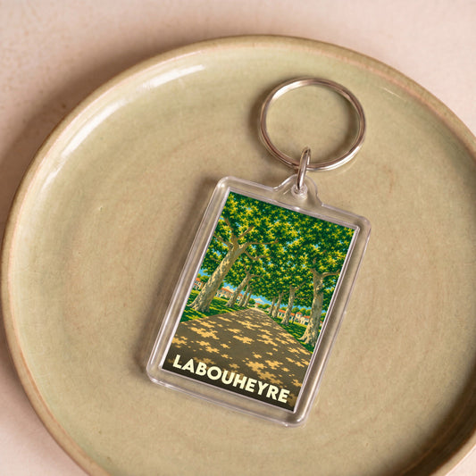 Porte-clés souvenir de la ville de Labouheyre avec une illustration stylisée d'une allée d'arbres.