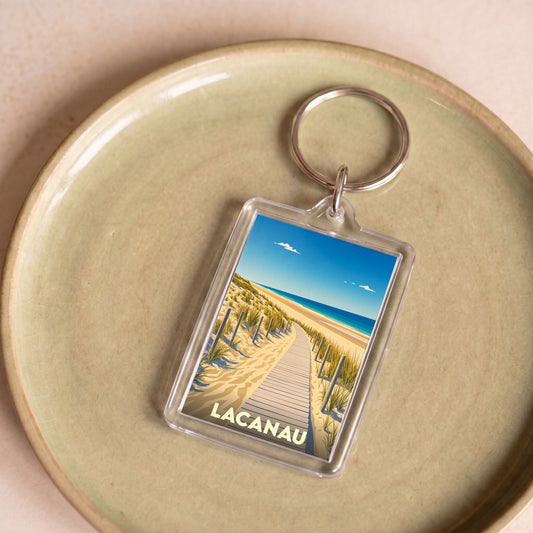 Porte-clés souvenir de la ville de Lacanau avec une illustration stylisée d'un chemin de plage.