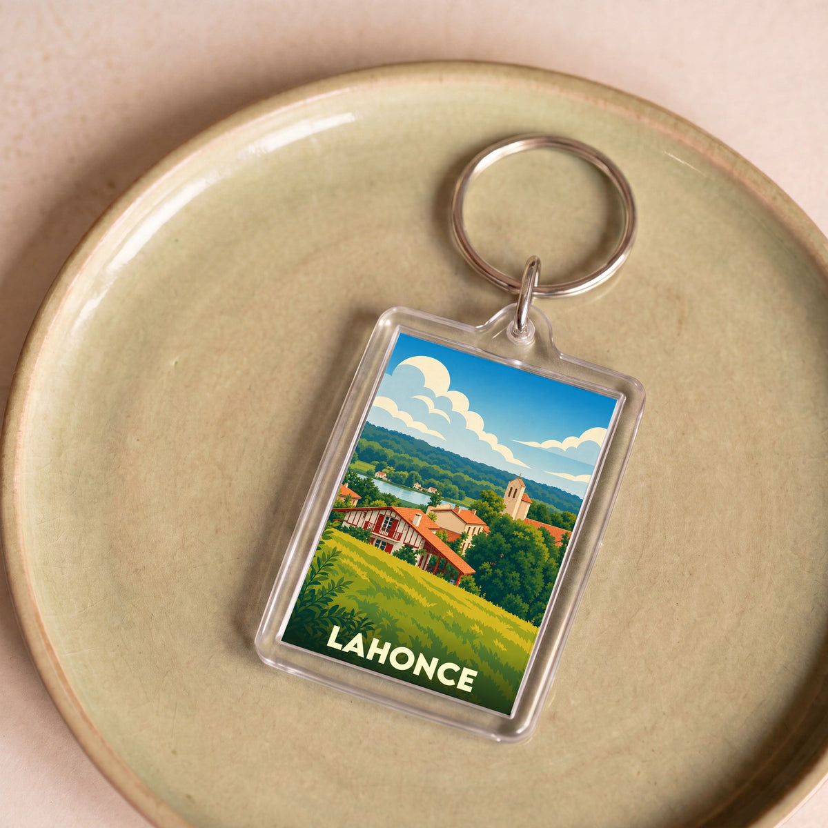 Porte-clés souvenir de la ville de Lahonce avec une illustration stylisée et colorée du paysage local.