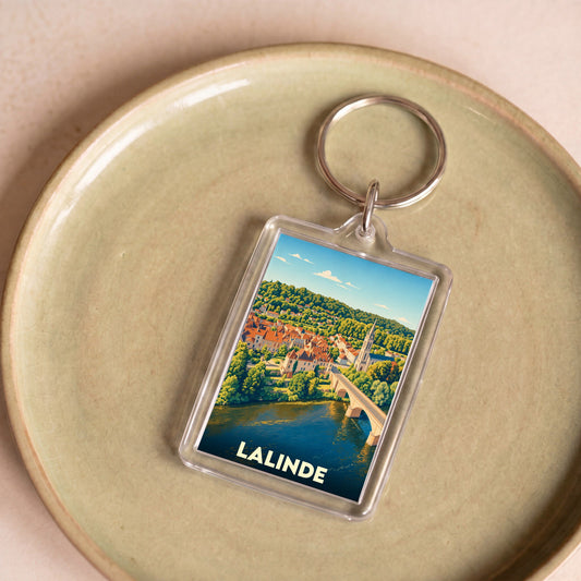 Porte-clés souvenir de la ville de Lalinde avec une illustration stylisée de son pont et de ses toits.