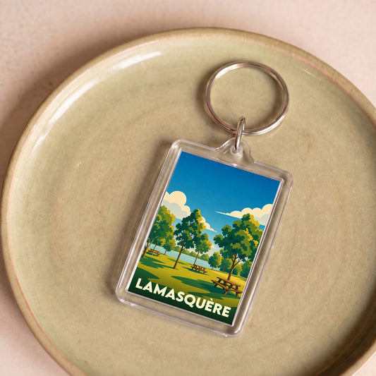 Porte-clés souvenir de la ville de Lamasquère avec une illustration stylisée d'un parc arboré.