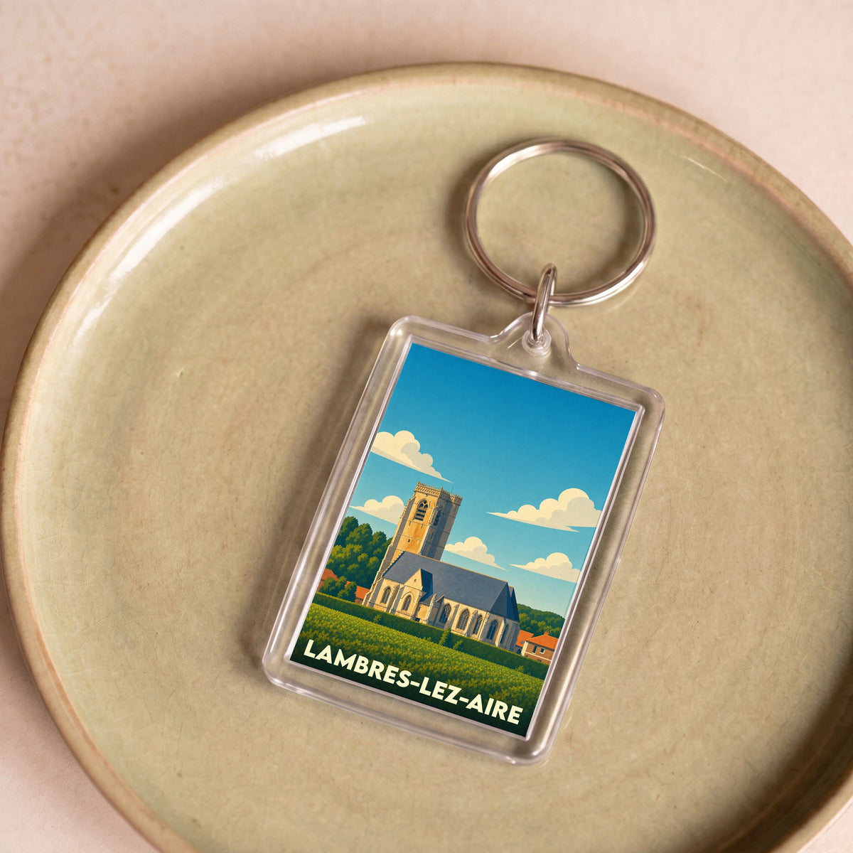 Porte-clés souvenir de la ville de Lambres-lez-Aire avec une illustration stylisée de son église.