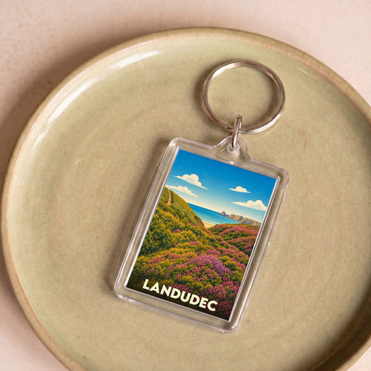 Porte-clés souvenir de la ville de Landudec avec une illustration stylisée d'un paysage côtier fleuri.