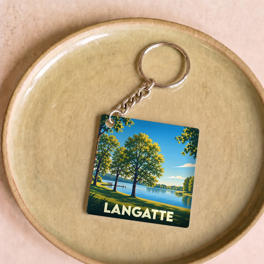 Porte-clés souvenir de la ville de Langatte avec une illustration stylisée de son lac et de sa forêt.