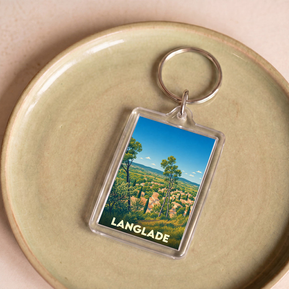 Porte-clés souvenir de la ville de Langlade avec une illustration stylisée d'un paysage provençal.