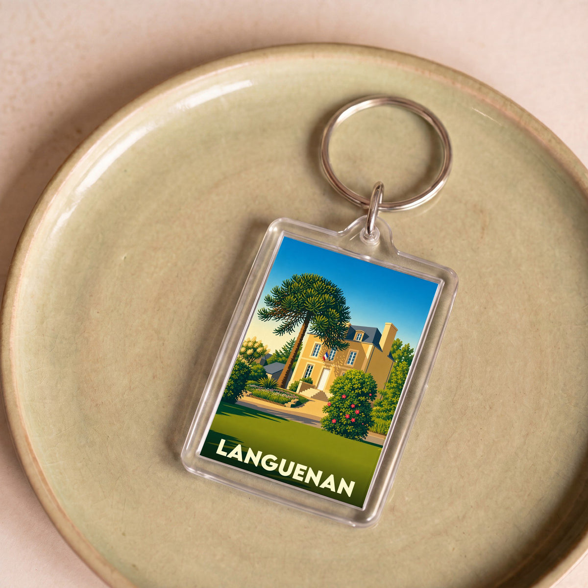 Porte-clés souvenir de la ville de Languenan avec une illustration stylisée d'une maison et d'un araucaria.