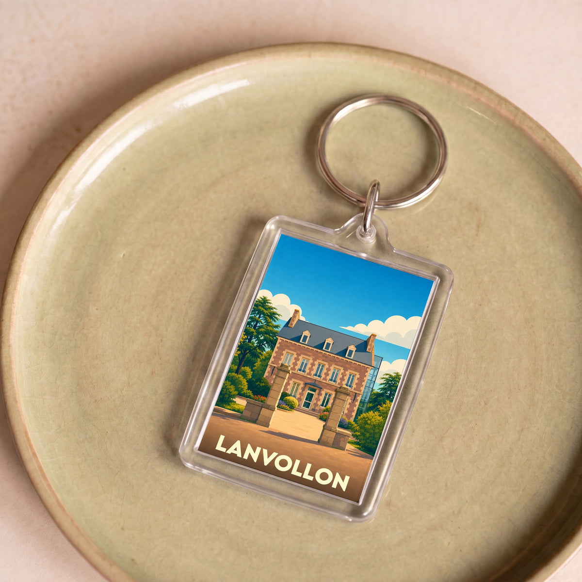 Porte-clés souvenir de la ville de Lanvollon avec une illustration stylisée d'un manoir breton.