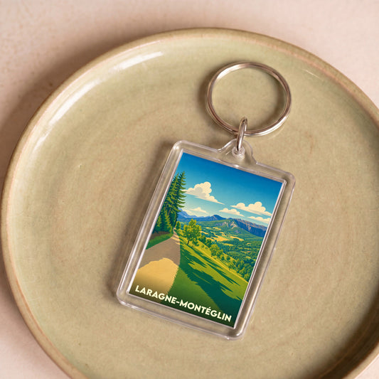 Porte-clés souvenir de la ville de Laragne-Montéglin avec une illustration de paysage montagneux stylisée.