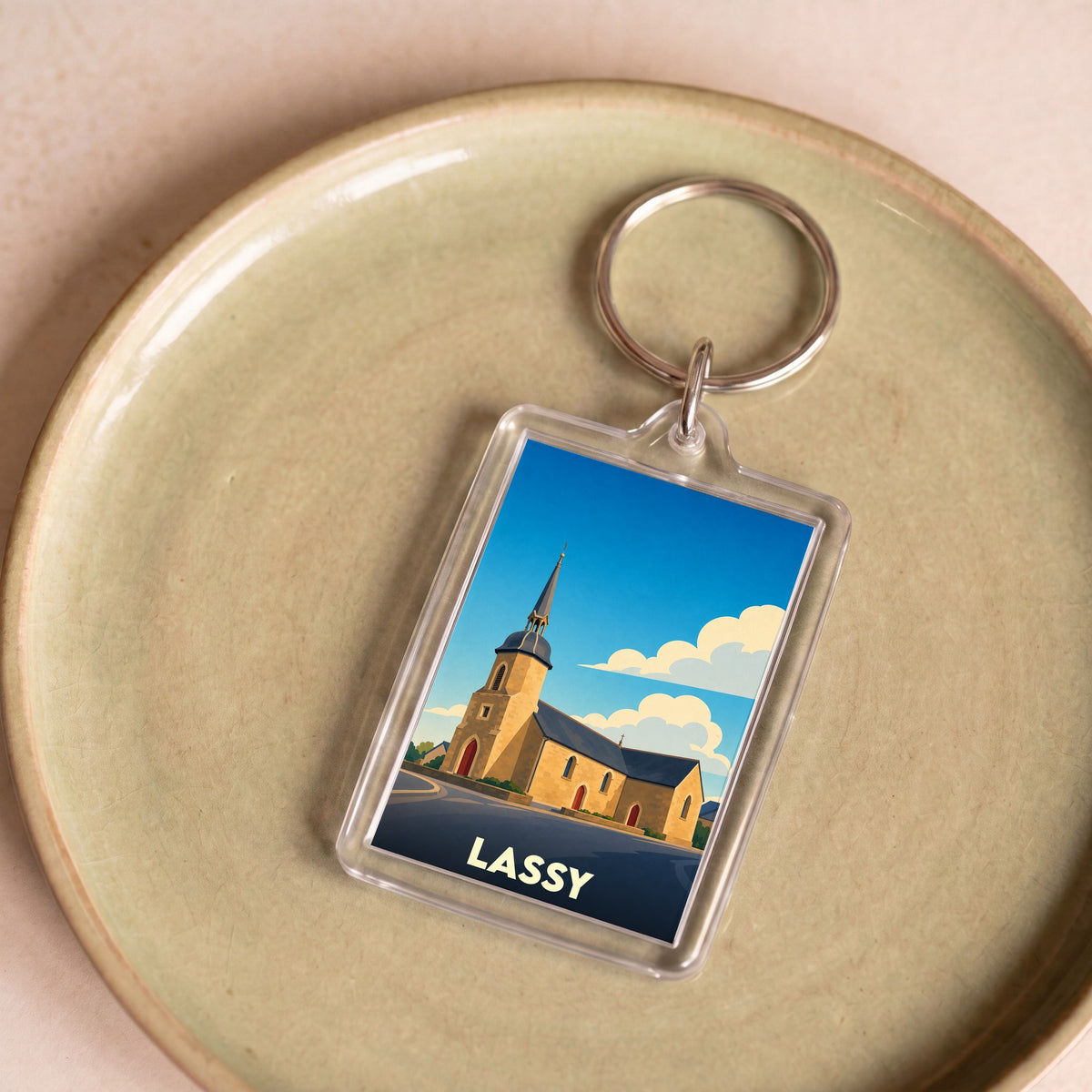 Porte-clés souvenir de la ville de Lassy avec une illustration stylisée de son église.