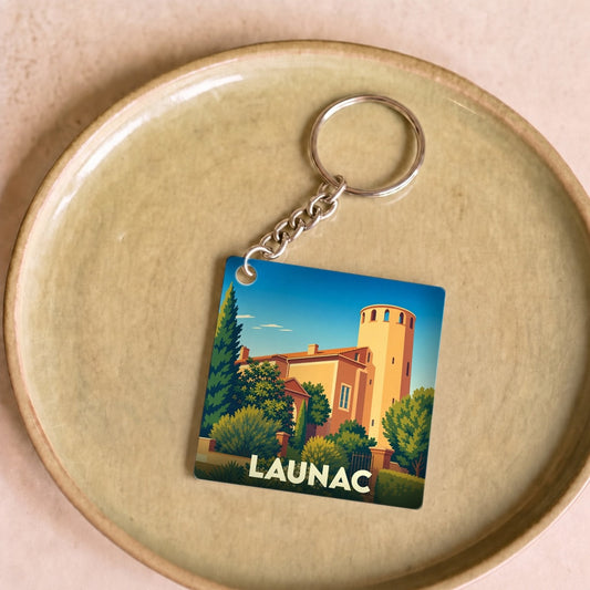 Porte-clés souvenir de la ville de Launac avec une illustration stylisée d'un bâtiment historique.