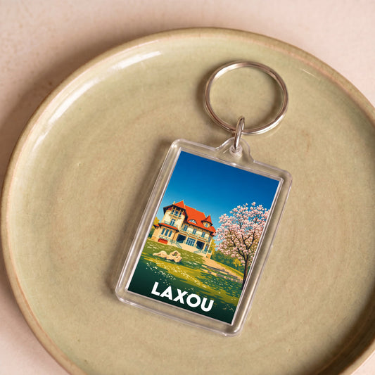 Porte-clés souvenir de la ville de Laxou avec une illustration stylisée.