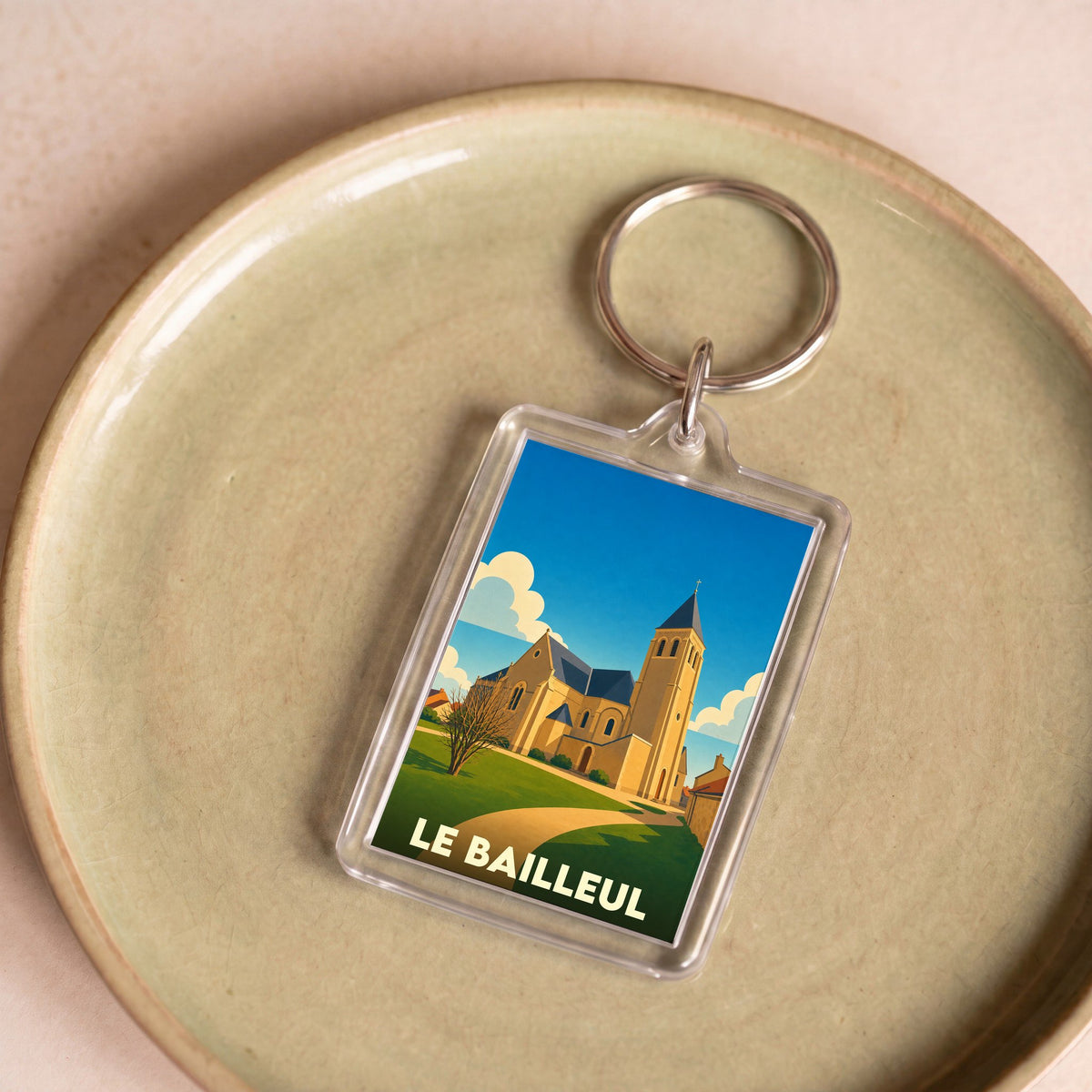 Porte-clés souvenir de la ville de Le Bailleul avec une illustration stylisée de son église.