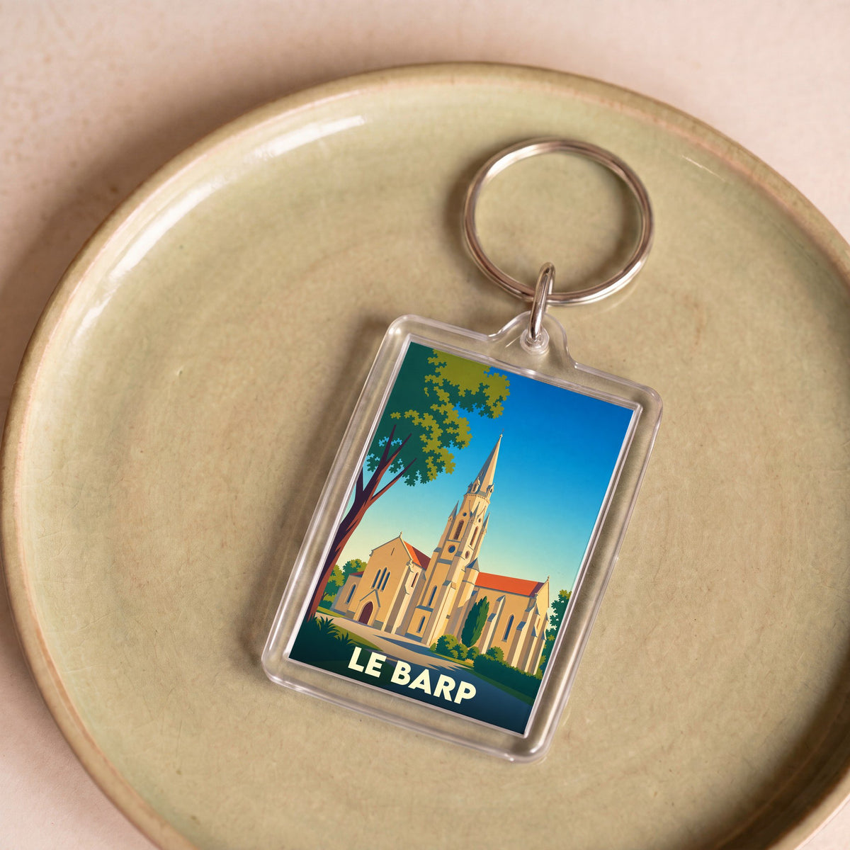 Porte-clés souvenir de la ville du Barp avec une illustration stylisée de son église.