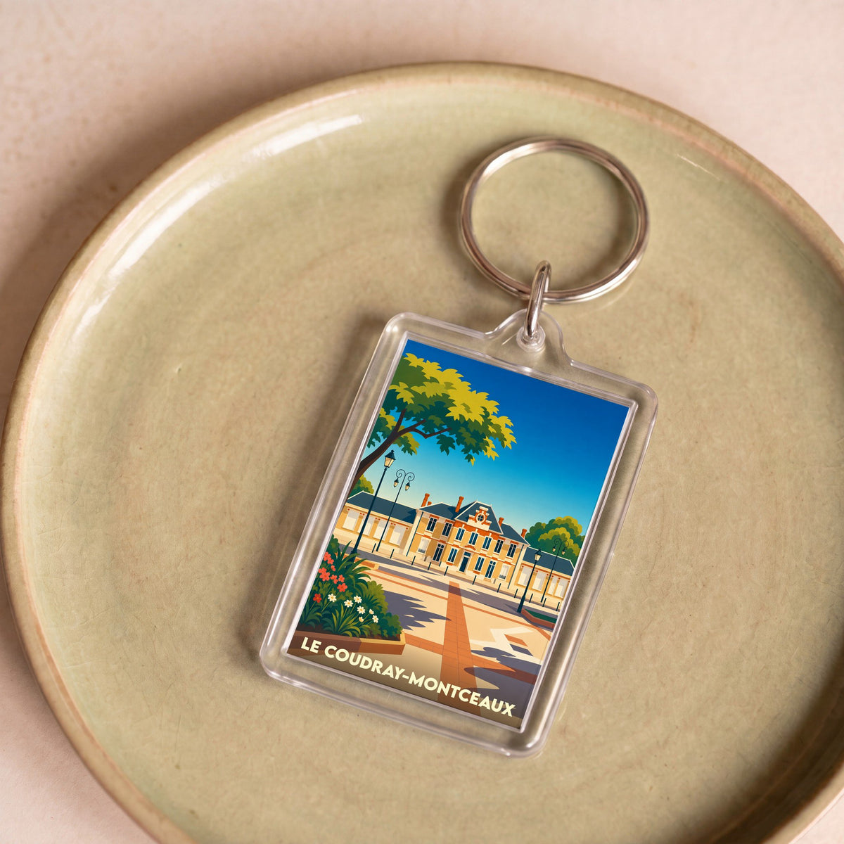 Porte-clés souvenir de la ville de Le Coudray-Montceaux avec une illustration stylisée.