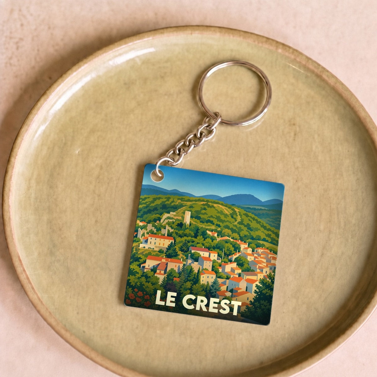 Porte-clés souvenir de la ville de Le Crest avec une illustration stylisée de ses paysages vallonnés.