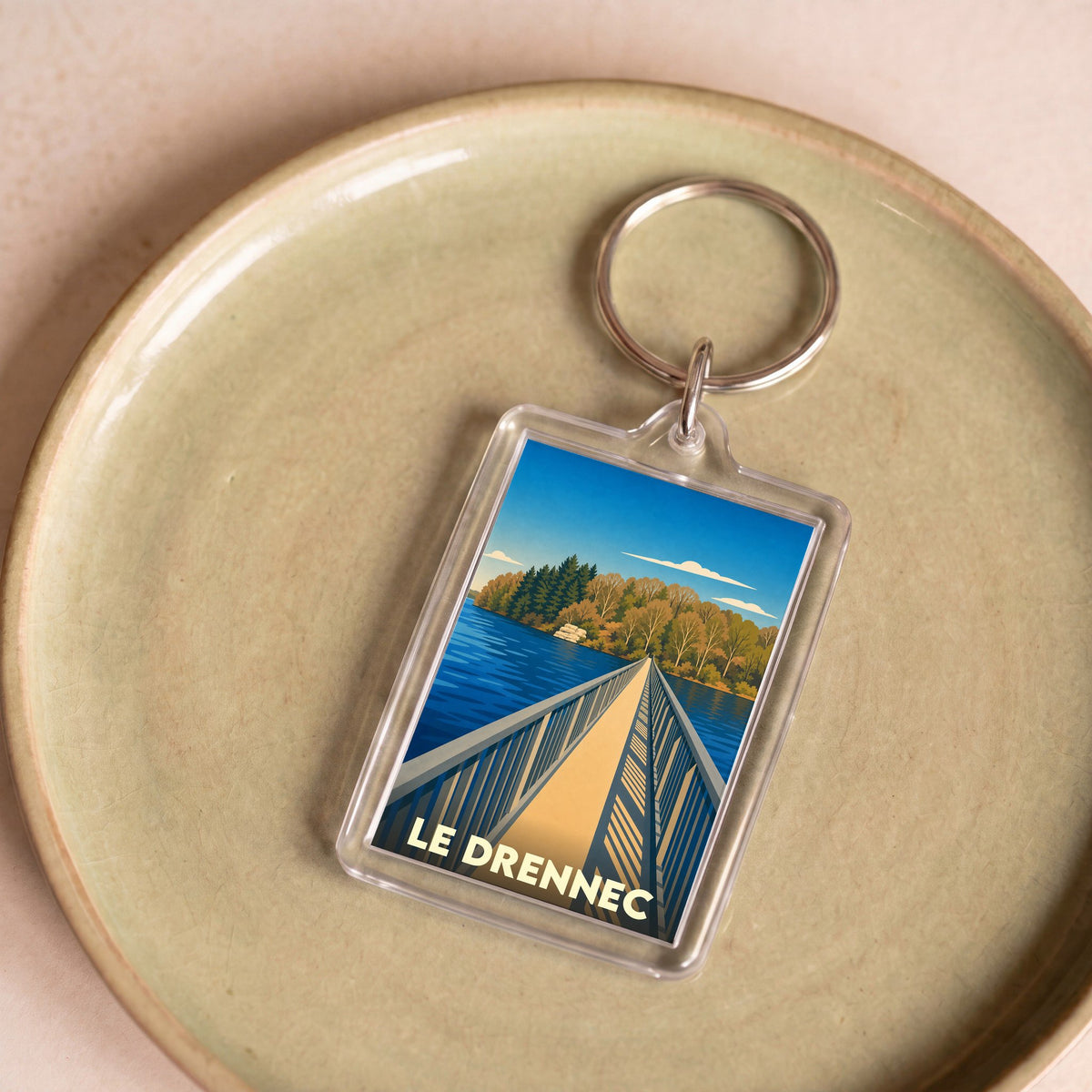 Porte-clés souvenir de la ville de Le Drennec avec une illustration stylisée d'un pont sur un lac.
