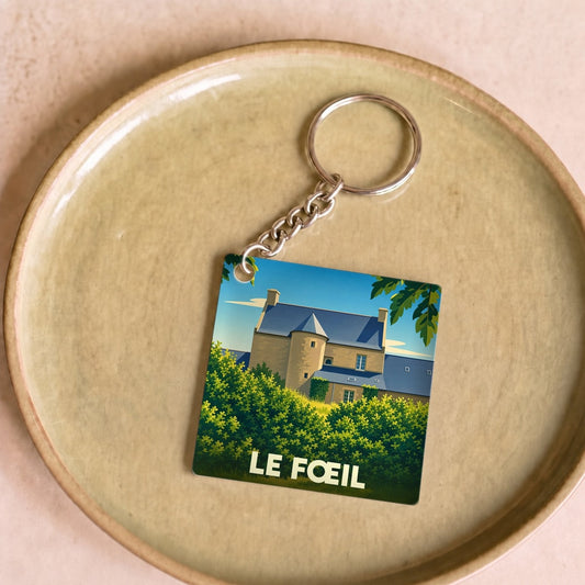 Porte-clés souvenir de la commune de Le Fœil avec une illustration stylisée de son patrimoine architectural.