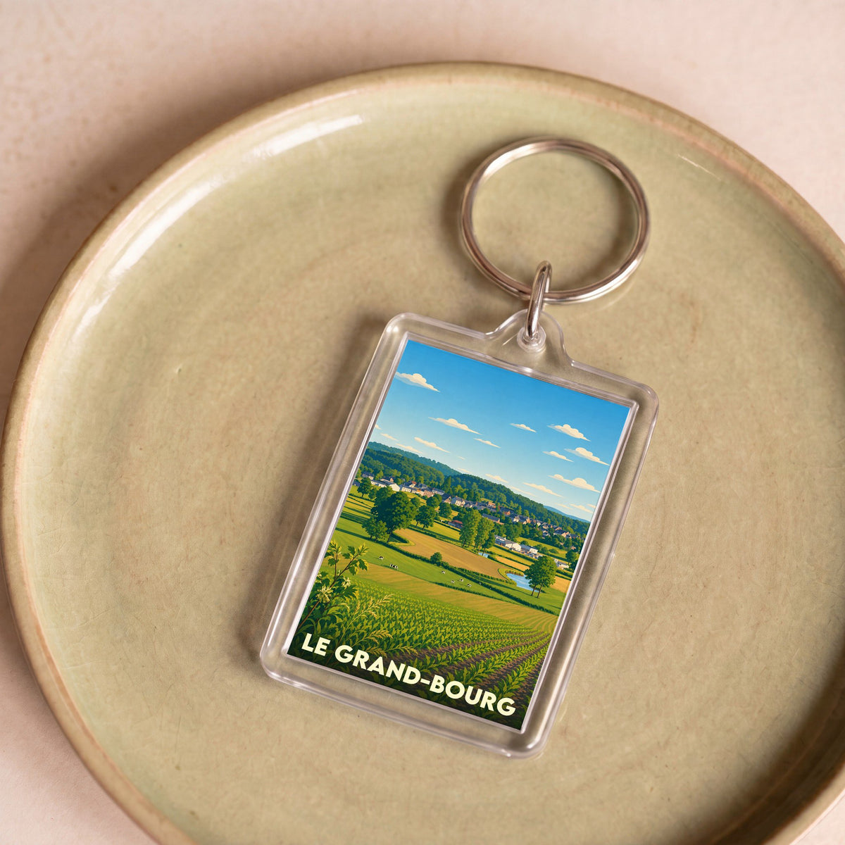 Porte-clés souvenir de la ville de Le Grand-Bourg avec une illustration champêtre stylisée.