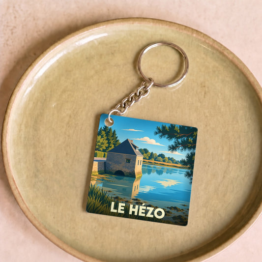 Porte-clés souvenir de la ville de Le Hézo avec une illustration stylisée d'un moulin à marée au bord de l'eau.