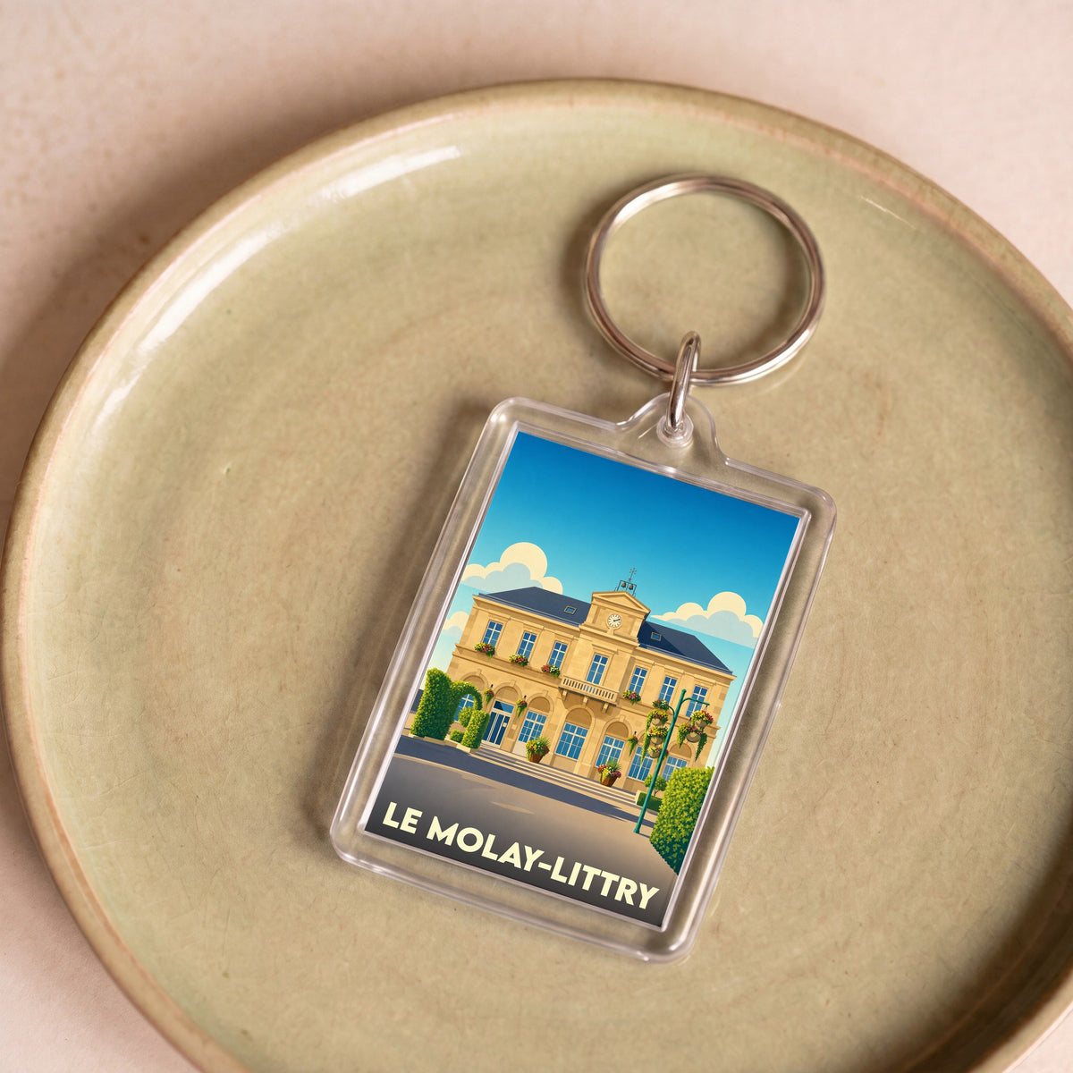 Porte-clés souvenir de la ville de Le Molay-Littry avec une illustration stylisée de sa mairie.