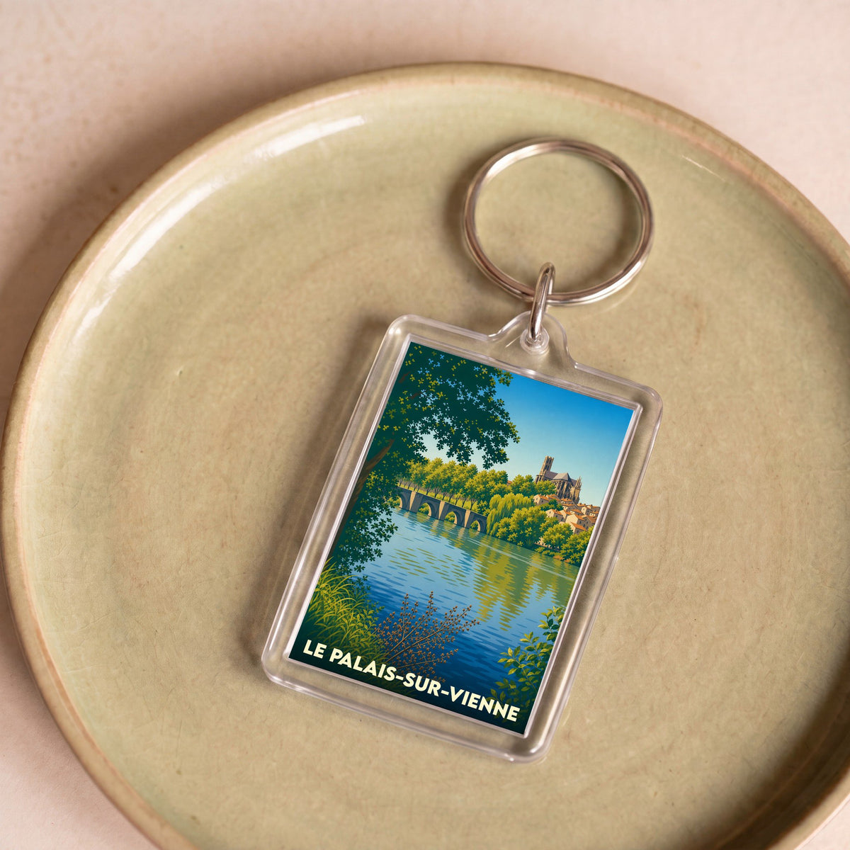 Porte-clés souvenir de la ville de Le Palais-sur-Vienne avec une illustration stylisée d'un paysage fluvial.