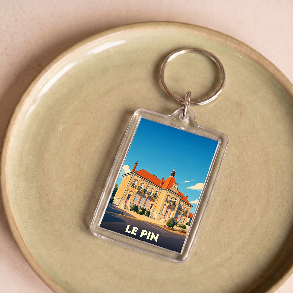 Porte-clés souvenir de la ville de Le Pin avec une illustration stylisée de sa mairie.