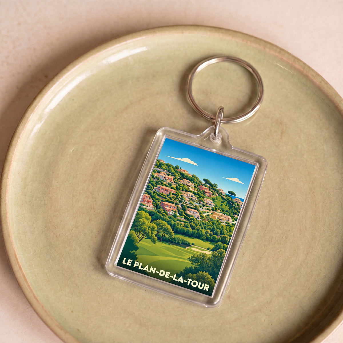 Porte-clés souvenir de la ville de Le Plan-de-la-Tour avec une illustration stylisée d'un paysage provençal.