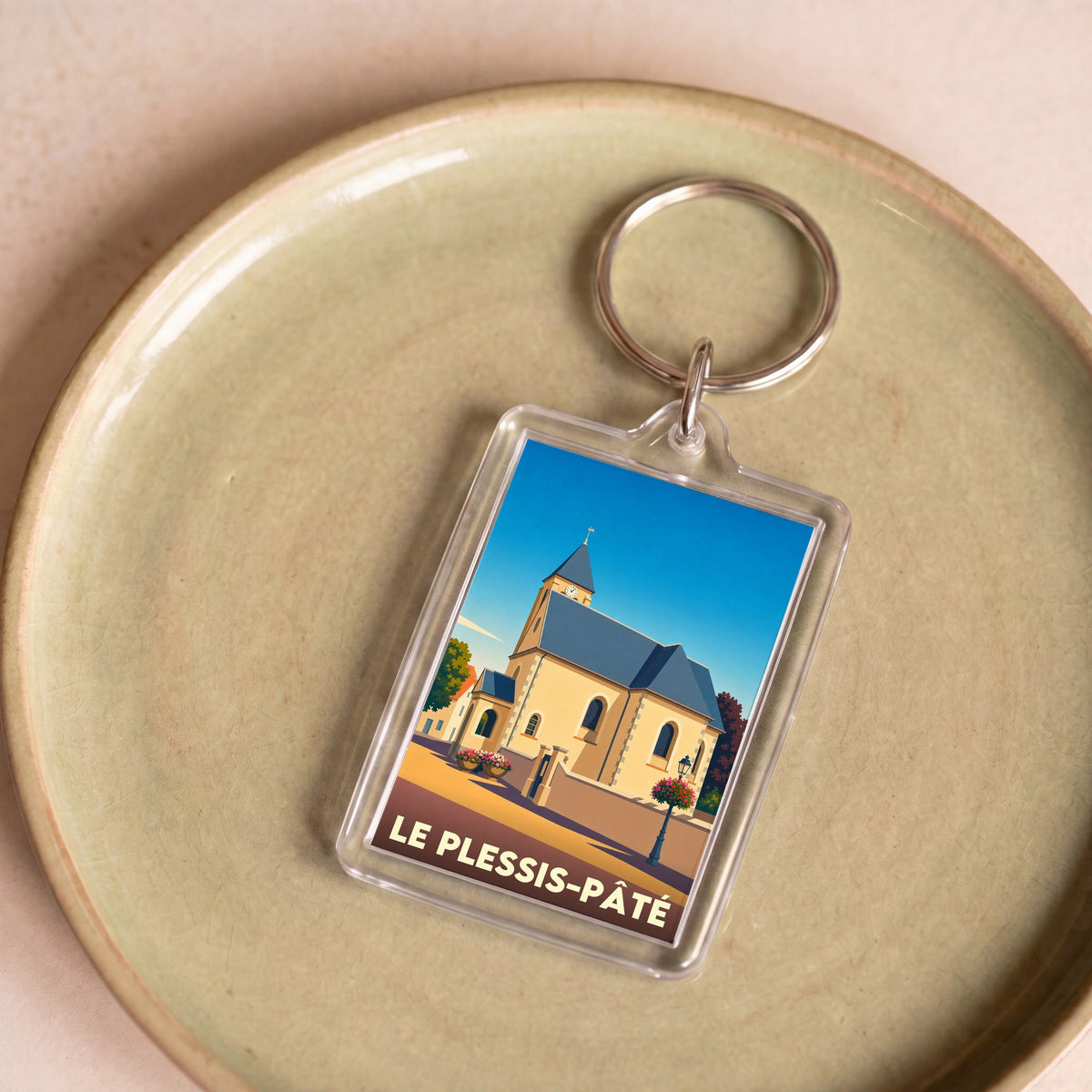 Porte-clés souvenir de la ville de Le Plessis-Pâté avec une illustration stylisée de son église.