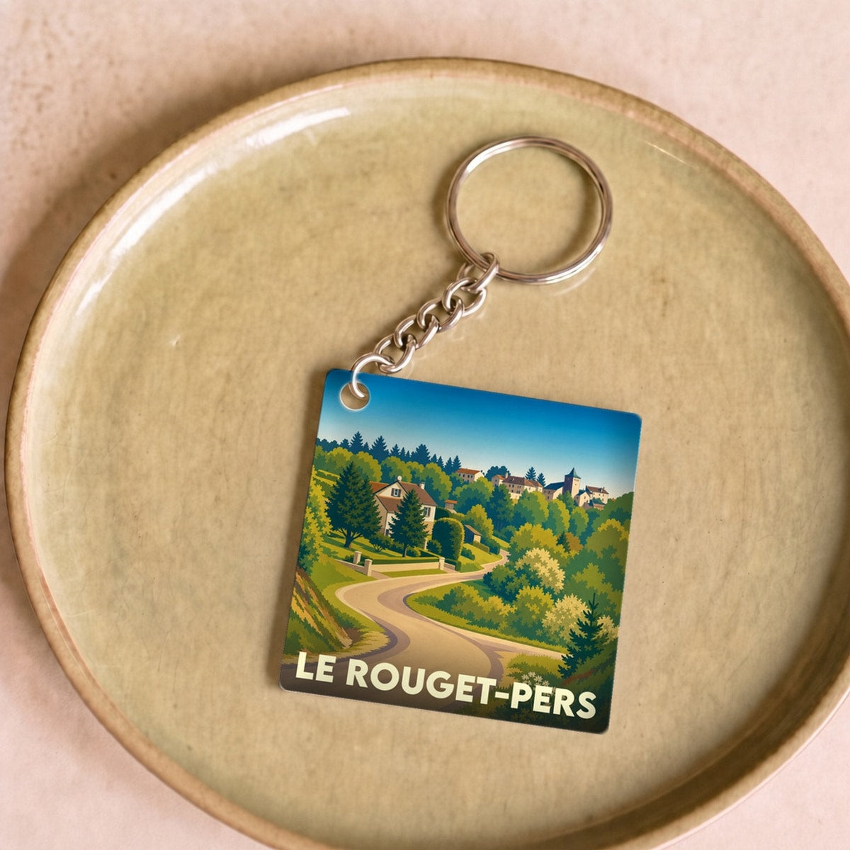 Porte-clés souvenir de la ville de Le Rouget-Pers avec une illustration stylisée de son paysage vallonné.