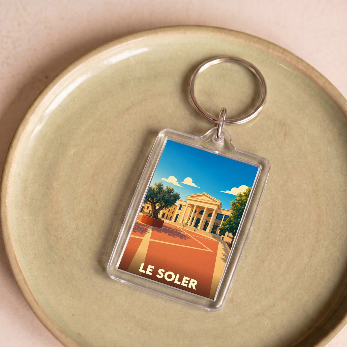 Porte-clés souvenir de la ville de Le Soler avec une illustration stylisée.