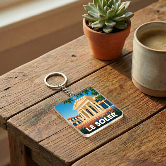 Porte-clés souvenir de la ville de Le Soler avec une illustration stylisée.