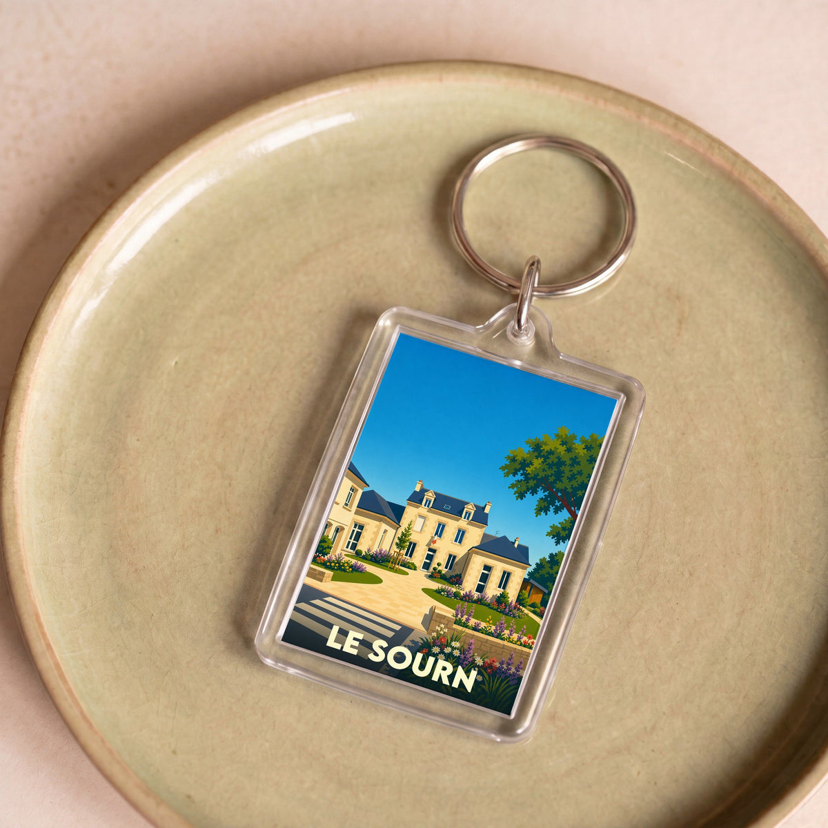 Porte-clés souvenir de la ville de Le Sourn avec une illustration stylisée.