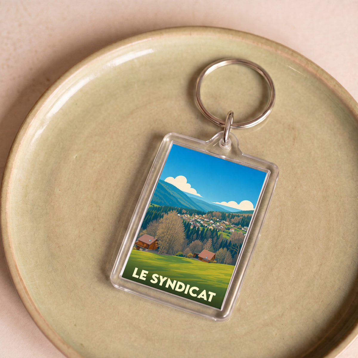 Porte-clés souvenir de la ville de Le Syndicat avec une illustration stylisée de paysages vosgiens.