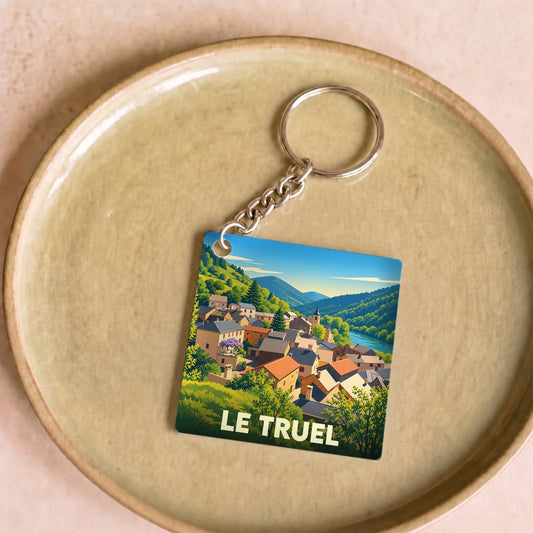 Porte-clés souvenir de la ville de Le Truel avec une illustration stylisée de son paysage montagneux.