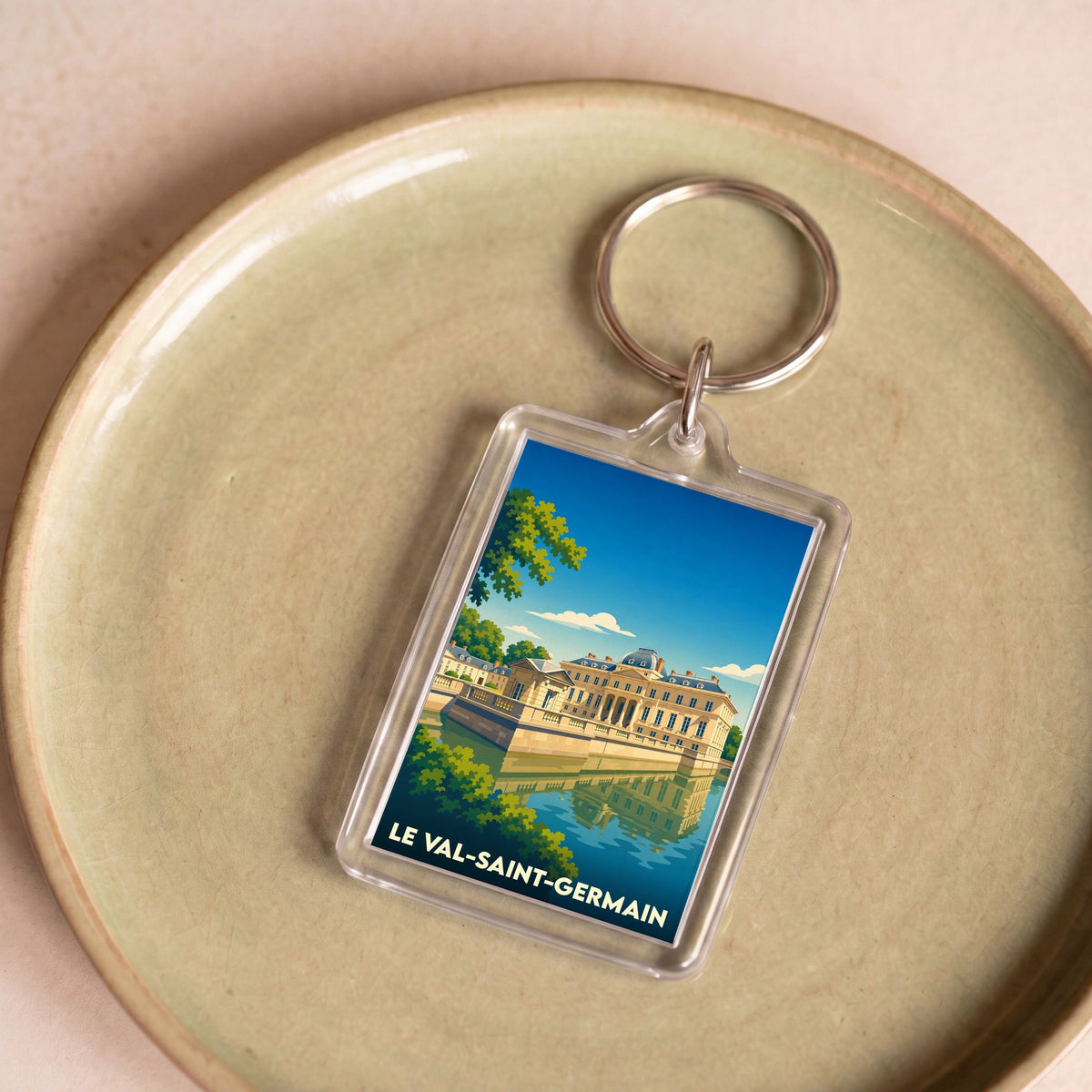 Porte-clés souvenir de la ville de Le Val-Saint-Germain avec une illustration stylisée d'un château se reflétant dans l'eau.
