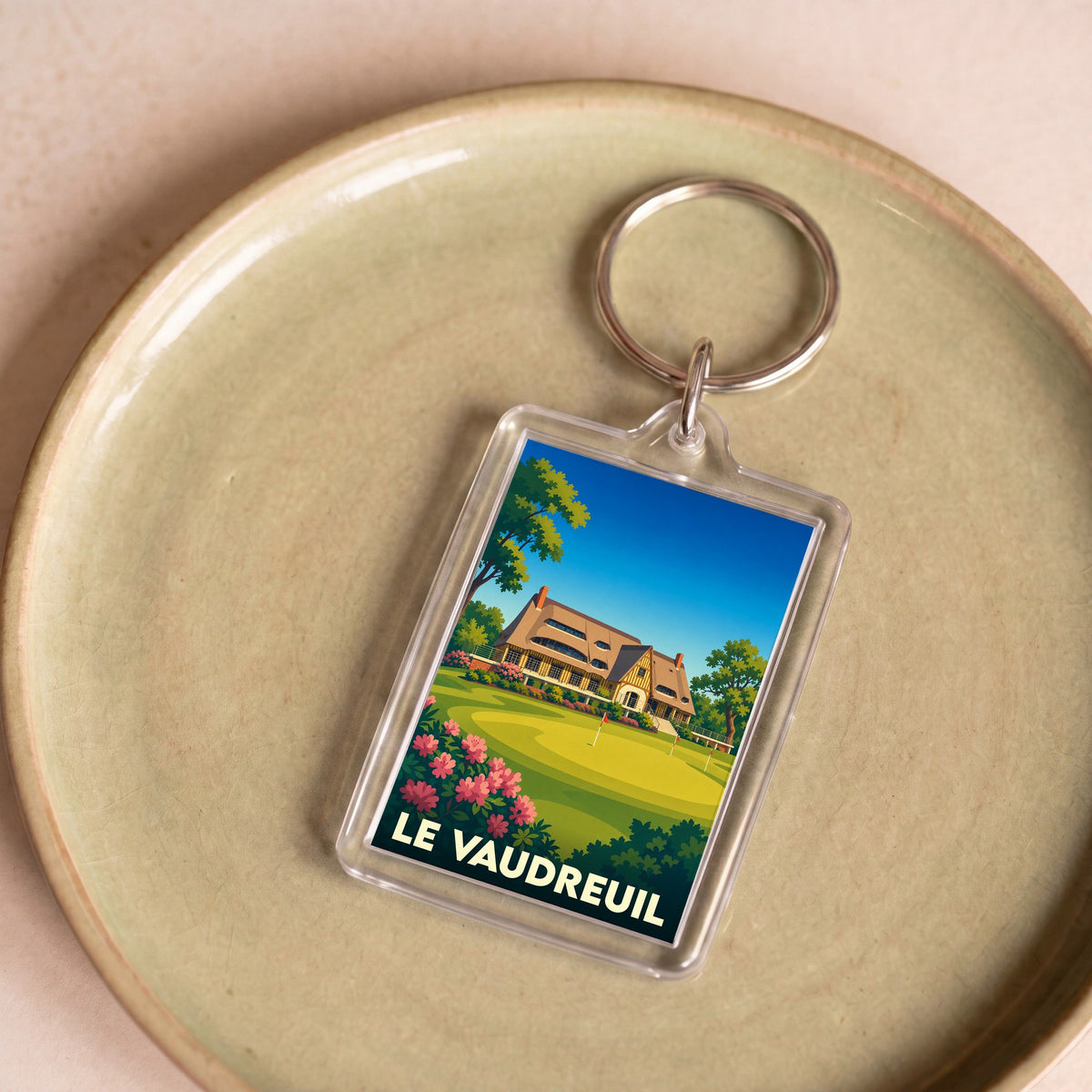 Porte-clés souvenir de la ville de Le Vaudreuil avec une illustration stylisée d'un parcours de golf.