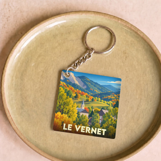 Porte-clés souvenir de la ville du Vernet avec une illustration stylisée de paysages montagneux en automne.