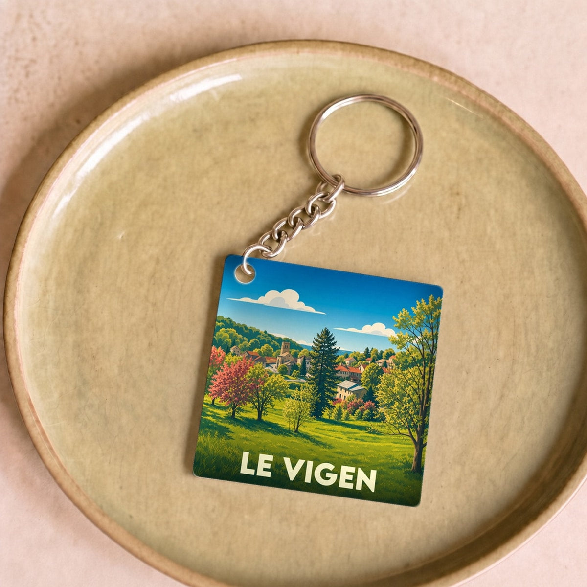 Porte-clés souvenir de la ville de Le Vigen avec une illustration paysagère stylisée.
