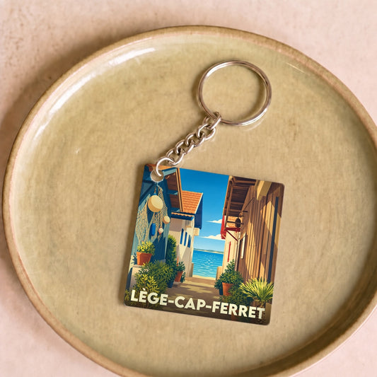 Porte-clés souvenir de la ville de Lège-Cap-Ferret avec une illustration stylisée de cabanes d'ostréiculteurs.