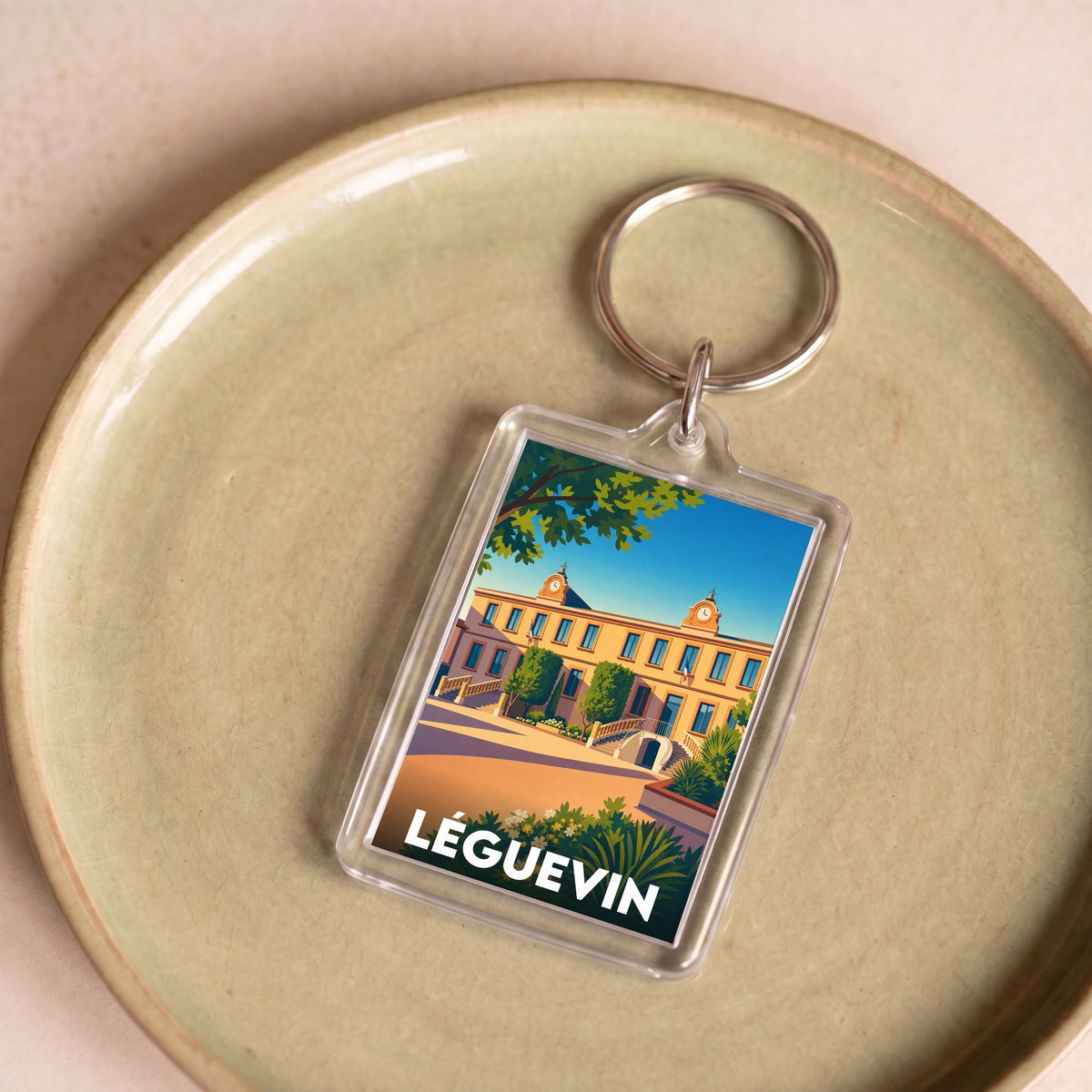 Porte-clés souvenir de la ville de Léguevin avec une illustration stylisée.