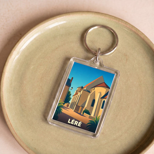 Porte-clés souvenir de la ville de Léré avec une illustration stylisée de son église sous un ciel bleu.