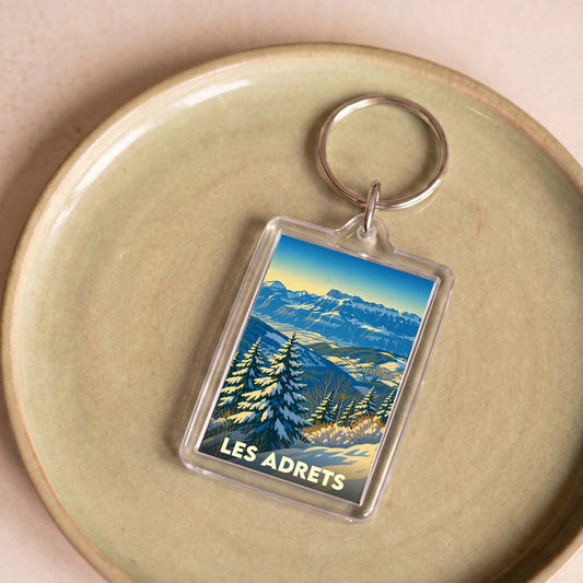 Porte-clés souvenir de la ville de Les Adrets avec une illustration de paysage montagneux enneigé.