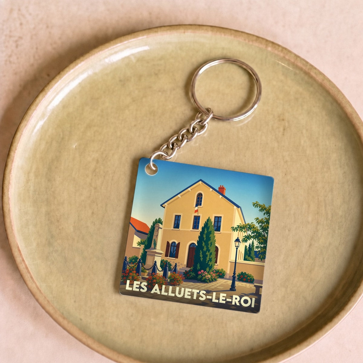 Porte-clés souvenir de la ville de Les Alluets-le-Roi avec une illustration stylisée.