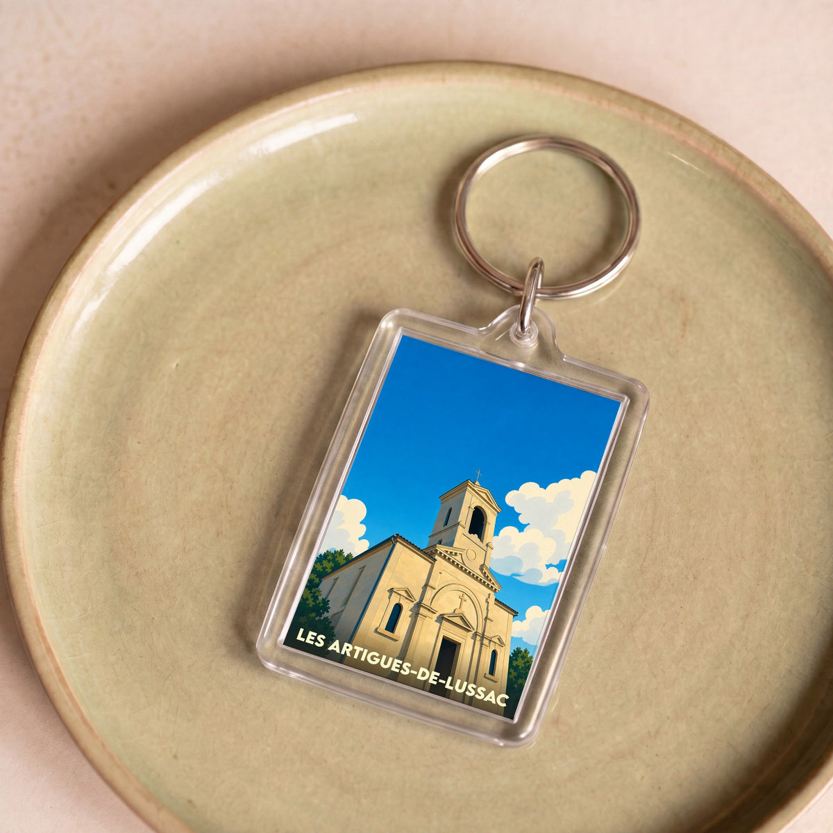 Porte-clés souvenir de la ville de Les Artigues-de-Lussac avec une illustration stylisée de son église.