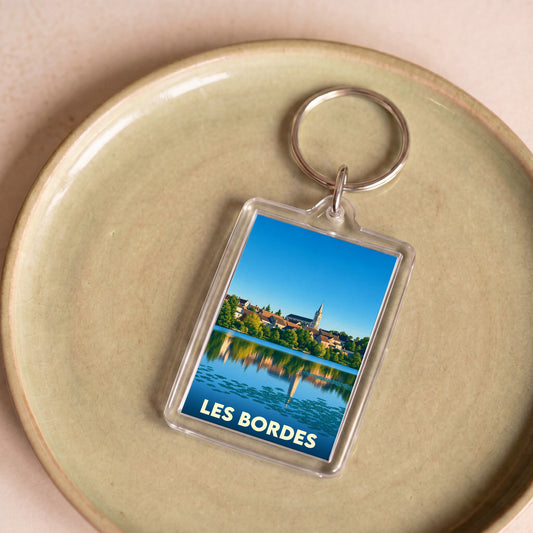 Porte-clés souvenir de la ville de Les Bordes avec une illustration stylisée d'un paysage au bord de l'eau.