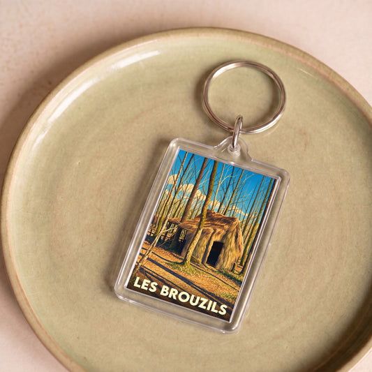 Porte-clés souvenir de la ville de Les Brouzils avec une illustration stylisée d'une cabane en forêt.
