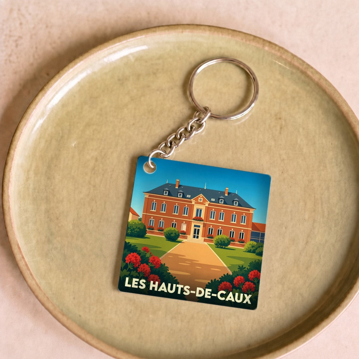 Porte-clés souvenir de la ville de Les Hauts-de-Caux avec une illustration stylisée d'un manoir normand.