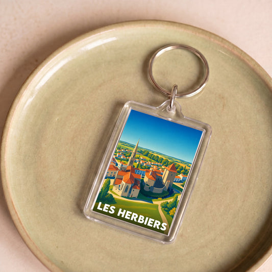 Porte-clés souvenir de la ville des Herbiers avec une illustration stylisée de son paysage urbain.