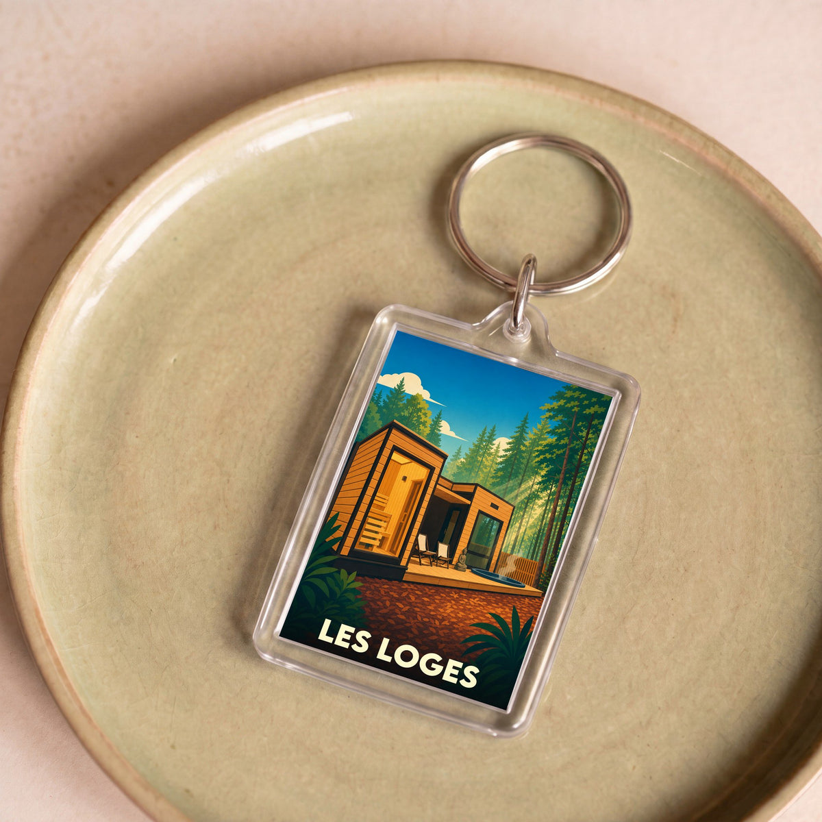 Porte-clés souvenir de la ville de Les Loges avec une illustration stylisée d'un hébergement insolite en forêt.